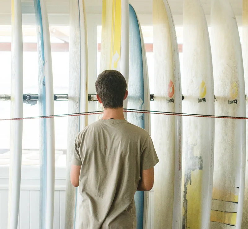 A guest choosing from a wall of surfboards inside the Baleal surf station